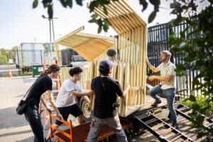 4 people installing a wooden structure.  North10 Heat Islands - Shelter Construction and Installation