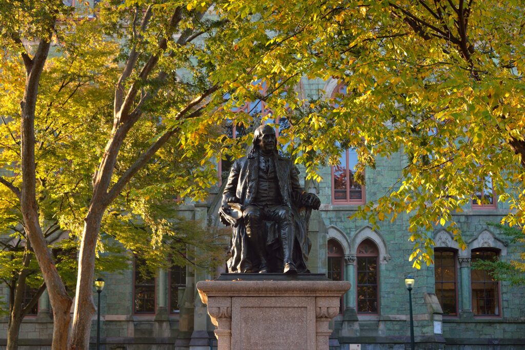 photo of the Ben Franklin statue on College Green on Penn's campus with the fall leaves